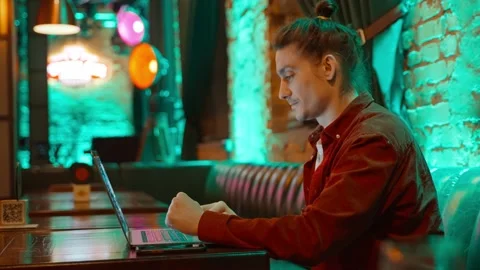 Young freelance guy working on a laptop in a cafe Stock Footage 232385243