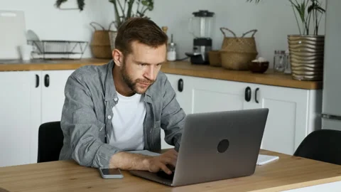 A Young Freelance Man Works At A Computer, Looks at The Monitor Screen Stock Footage 157053920