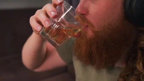 Young freelancer, gamer programmer drinks whiskey from a glass close-up. Stock Footage 278707970