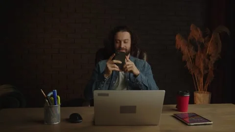 A young freelancer man with a beard at the workplace in the office is chatting Stock Footage 246748636