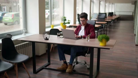 Young freelancer man working with laptop at bright spacious coworking alone Stock Footage 217734267