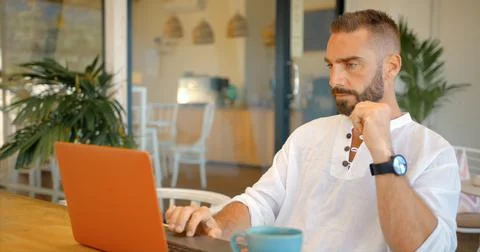 Young freelancer man working while rest in the open summer cafe, he is focused Stock Photos