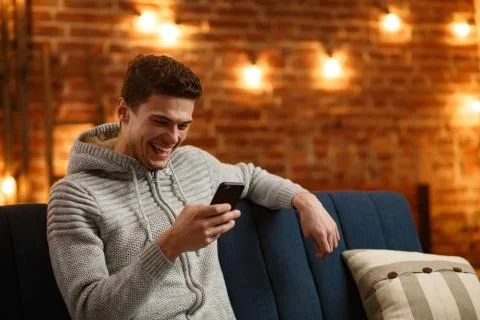 Young freelancer using smartphone and smiling. Happy man using mobile phone apps Foto stock