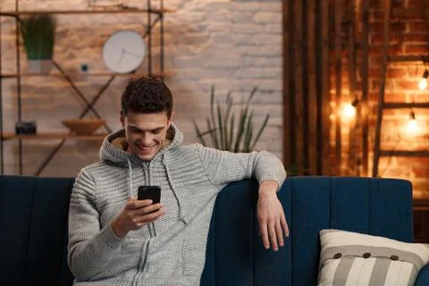 Young freelancer using smartphone and smiling. Happy man using mobile phone apps Stock Photos