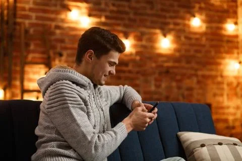 Young freelancer using smartphone and smiling. Happy man using mobile phone apps Stock Photos