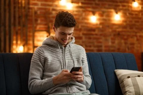 Young freelancer using smartphone and smiling. Happy man using mobile phone apps Stock Photos