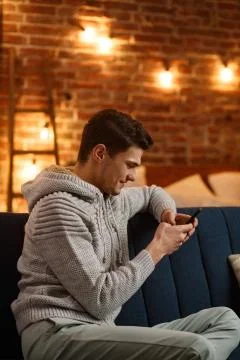 Young freelancer using smartphone and smiling. Happy man using mobile phone apps Stock Photos