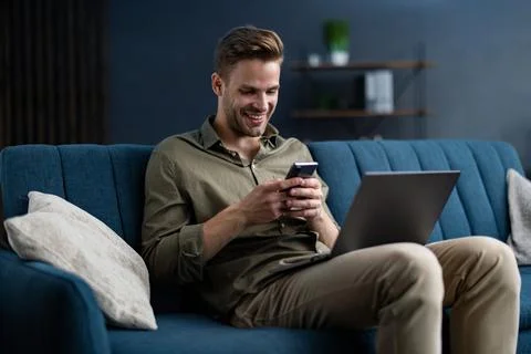 Young freelancer using smartphone and smiling. Happy man using mobile phone apps Stock Photos