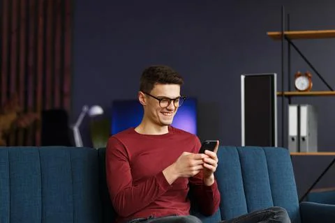 Young freelancer using smartphone and smiling. Happy man using m Stock Photos