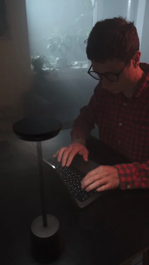 Young freelancer wearing glasses working on laptop under modern desk lamp Stock Footage 318442242