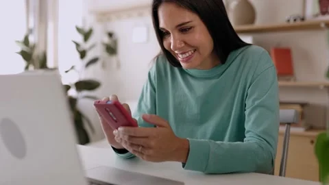 Young freelancer woman using mobile phone while working on laptop at home office Stock Footage 209586083