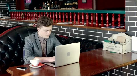 A young freelancer working at laptop in cafe Stock Footage 61388324