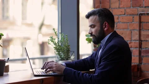 Young freelancer working with laptop sitting in cafe. Texting messages, browsing Stock Footage 166097776