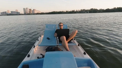 Young freelancer works on the computer on a boat. Remote Business. passive Video stock 98827455
