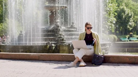 The young freelancer works on a modern computer outside in the park near a Stock Footage 232296309