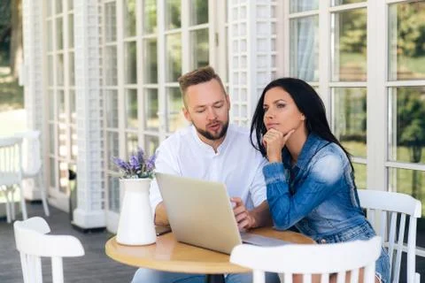 Young freelancers sit in a cafe outside, discuss their project, develop a Stock Photos