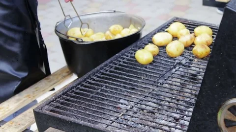 Young fresh potatoes that are laid out and turned over on a barbecue grill on Stock Footage