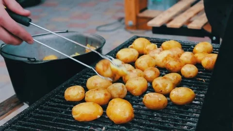 Young fresh potatoes that are laid out and turned over on a barbecue grill on Stock Footage