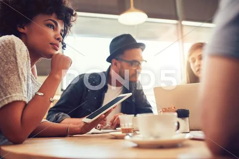 Young friends at a coffee shop with laptop and digital tablet Stock Photos
