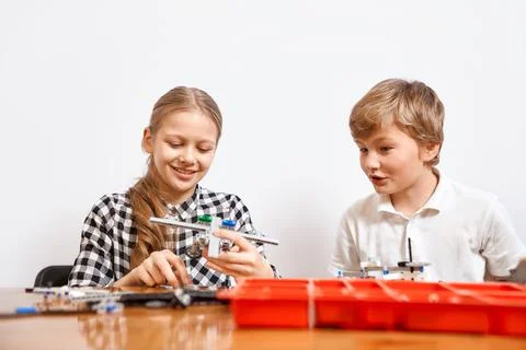 Young friends creating plane using building kit. Stock Photos