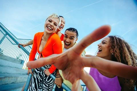 Young friends lean toward the camera and laugh by the waterfront Stock-Fotos