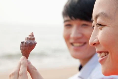 Young Friends Looking at Seashell Stock-Fotos