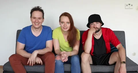 Young friends sit on the sofa and cheer Stock Footage 133574087