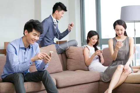 Young friends sitting on the sofa  with smart phones Foto stock