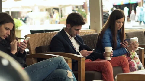 Young friends using smartphone sitting in cafe in city  HD Stock Footage 52971973