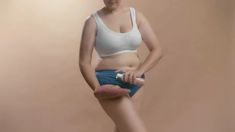 Young full-figured anonymous caucasian woman applying self-tanner to look Stock Footage 157427255