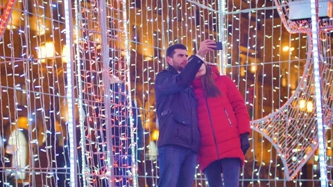 Young fun couple are doing selfie in the night city on a background of bright Stock Footage 76565002