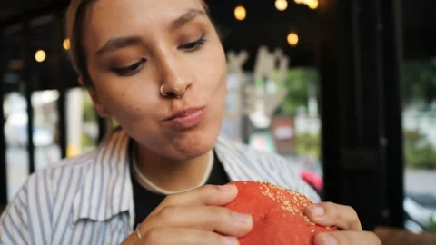 Young funny mixed race woman eating plant based vegan burger and enjoying each Stock Footage 236219682