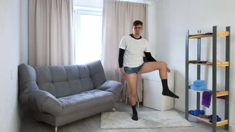 Young funny nerd man in glasses doing fitness exercises lifting legs at home. Stock Footage 159495832