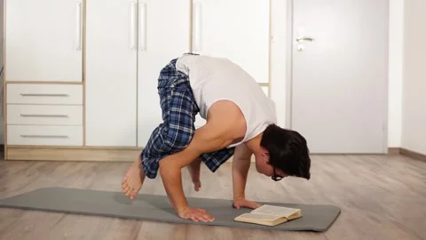 Young funny strong boy user standing in unusual pose acrobatic with book Vidéo 253826204