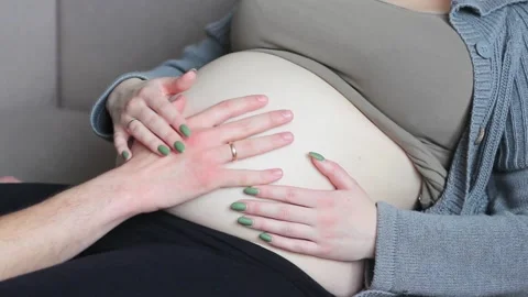 Young, future mom and dad are stroking a pregnant naked belly. Close-up. Stock Footage 152880410