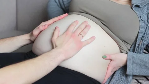 Young, future mom and dad are stroking a pregnant naked belly. Close-up. Stock Footage 152880638