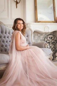 Young future mom sitting on sofa Stock Photos