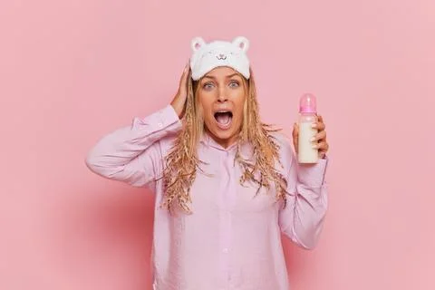 Young future mom standing over background in pink pyjamas, nerving crying and Foto stock
