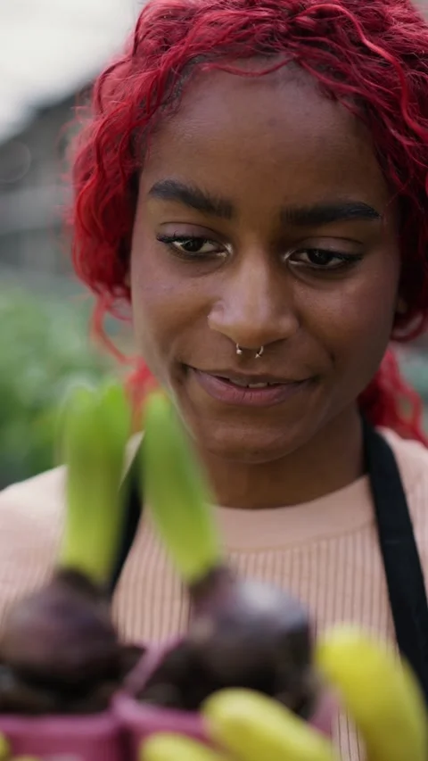 A young gardener smiles while nurturing colorful plants in a lively urban garden Stock Footage 310999262