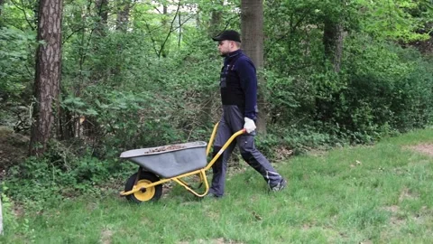 Young gardener in work overall walking with wheelbarrow 스톡 동영상 130659832