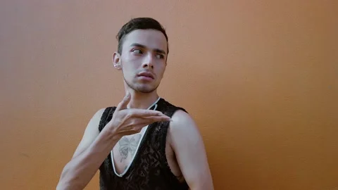 Young gay man doing hands performance on a coral colored background in a pan. Stock Footage 192079204