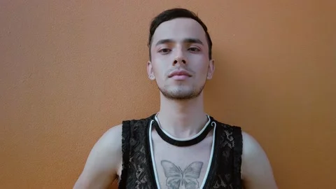 Young gay man posing seriously on a coral-colored wall. LGBT community. Stock Footage 192079158