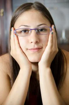 Young geeky girl with glasses and hands on a cheeks. Stock Photos