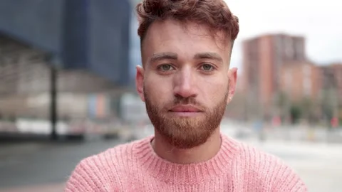 Young ginger man looking at camera outdoor with city on background Stock Footage 198219841