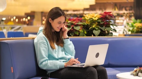 A young gir programmer sits in the lobby and looks at the laptop screen. She Stock Footage 121465503