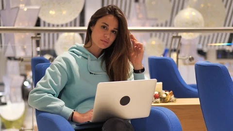 A young gir programmer sits in the lobby and looks at the laptop screen. She smi Stock Footage 126029658