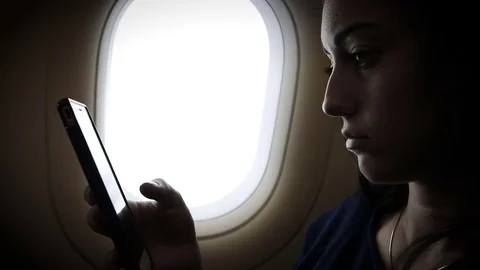 Young gir is using smartphone inside an airplane next to a window Stock Footage 83325402