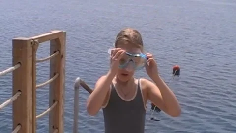 Young girl adjusting her diving mask on a sea pier Stock Footage 346147347