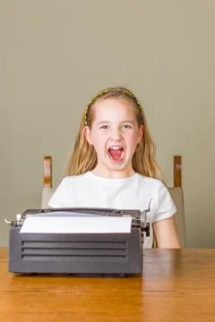 Young girl angry while working on old typewriter Stock Photos
