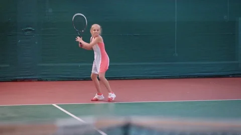 Young girl athlete in a sportive form actively discourages tennis balls Stock Footage